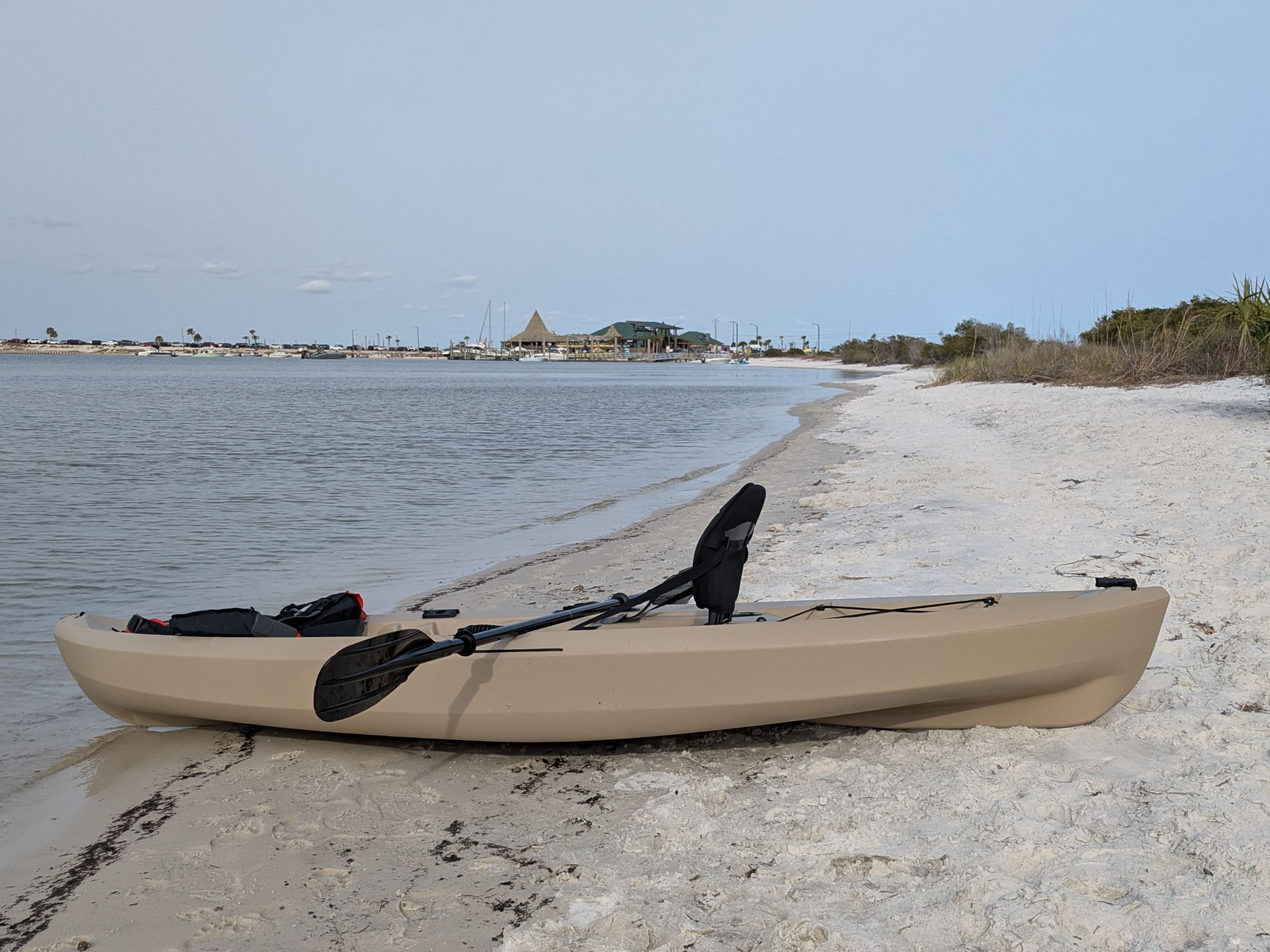 A kayak on a sandy beach with calm water in the background.