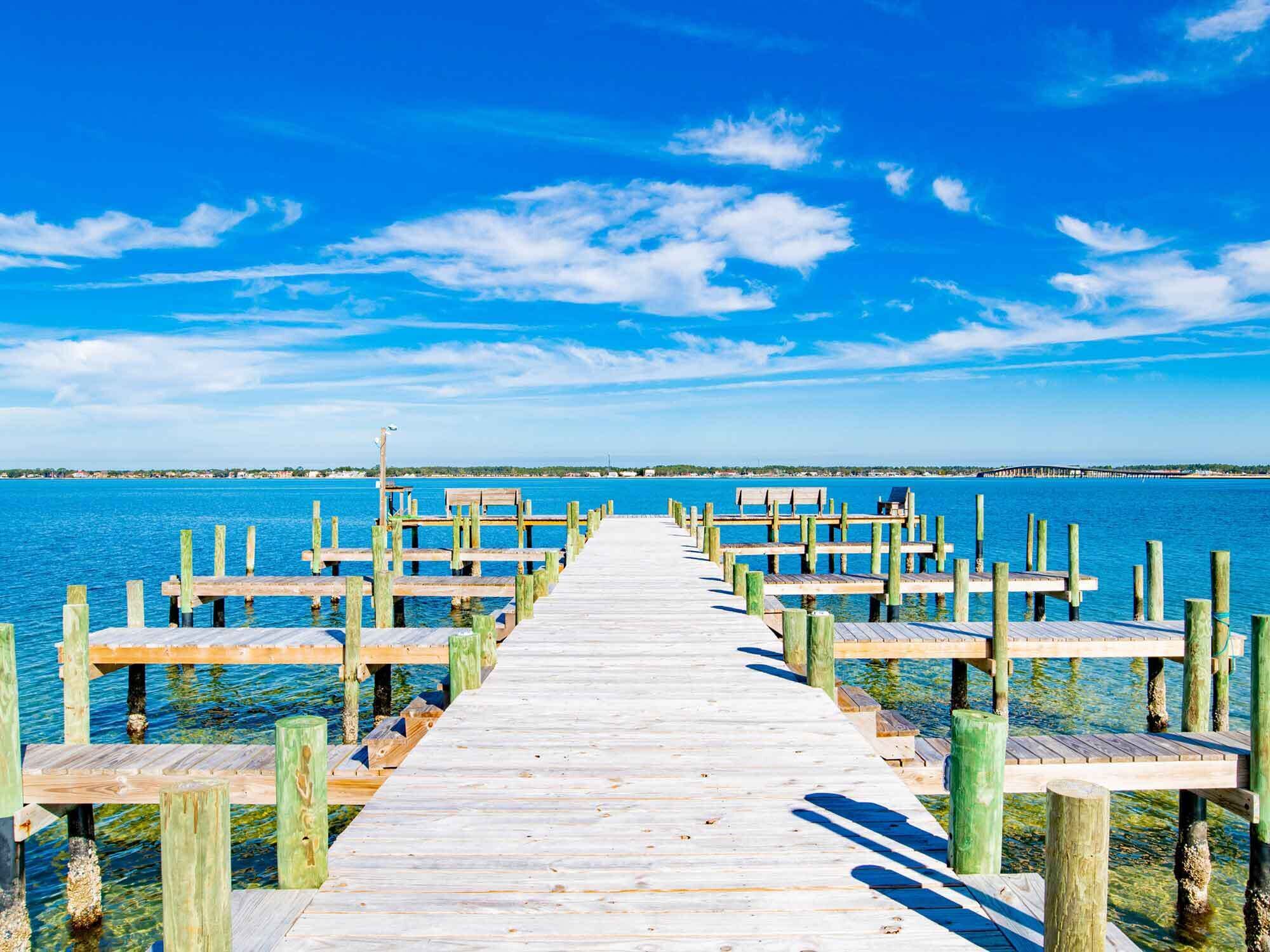 A wooden pier extending into a calm body of water, with a clear sky above.