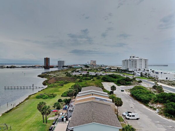 A coastal hotel with a parking lot, a beach, and a pier in the background. - Sabine Yacht & Racquet #8D by Southern Vacation Rentals (Pensacola Beach)