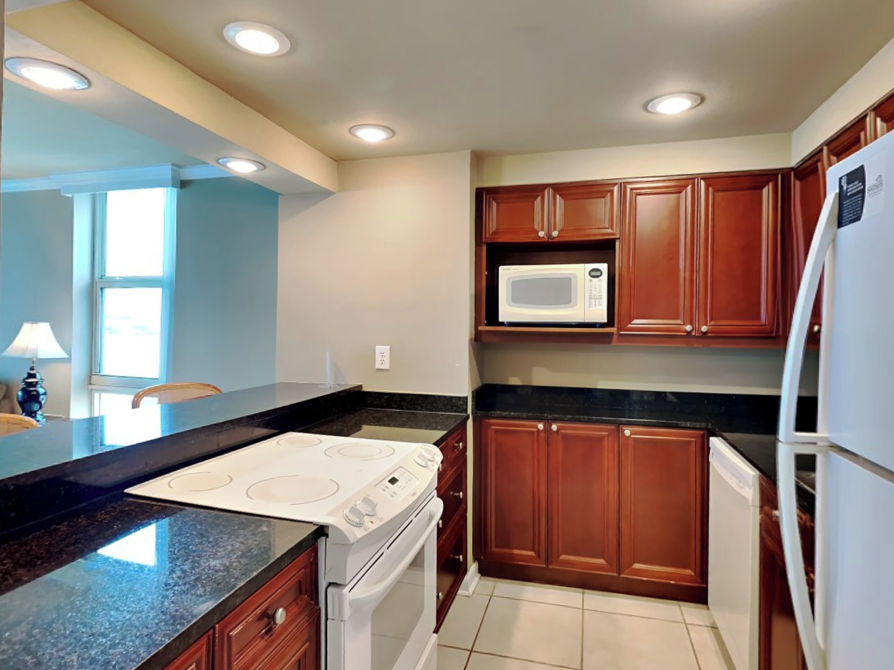 A kitchen with wooden cabinets, a microwave, a stove, and a refrigerator.