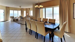 Ein geräumiges Wohnzimmer mit großem Esstisch, bequemen Sitzgelegenheiten und Blick auf den Ozean.