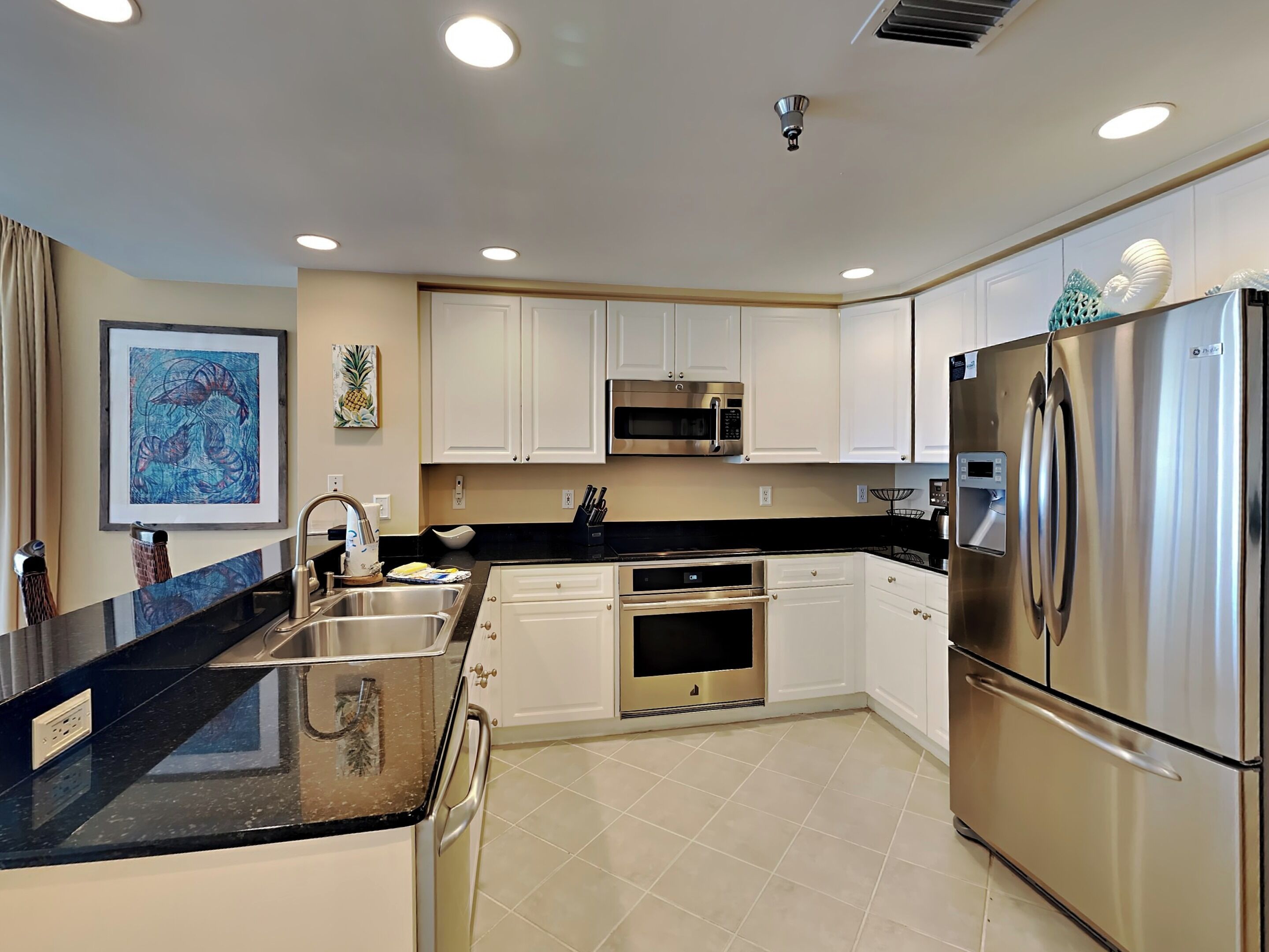 A modern kitchen with white cabinets, stainless steel appliances, and a black countertop.