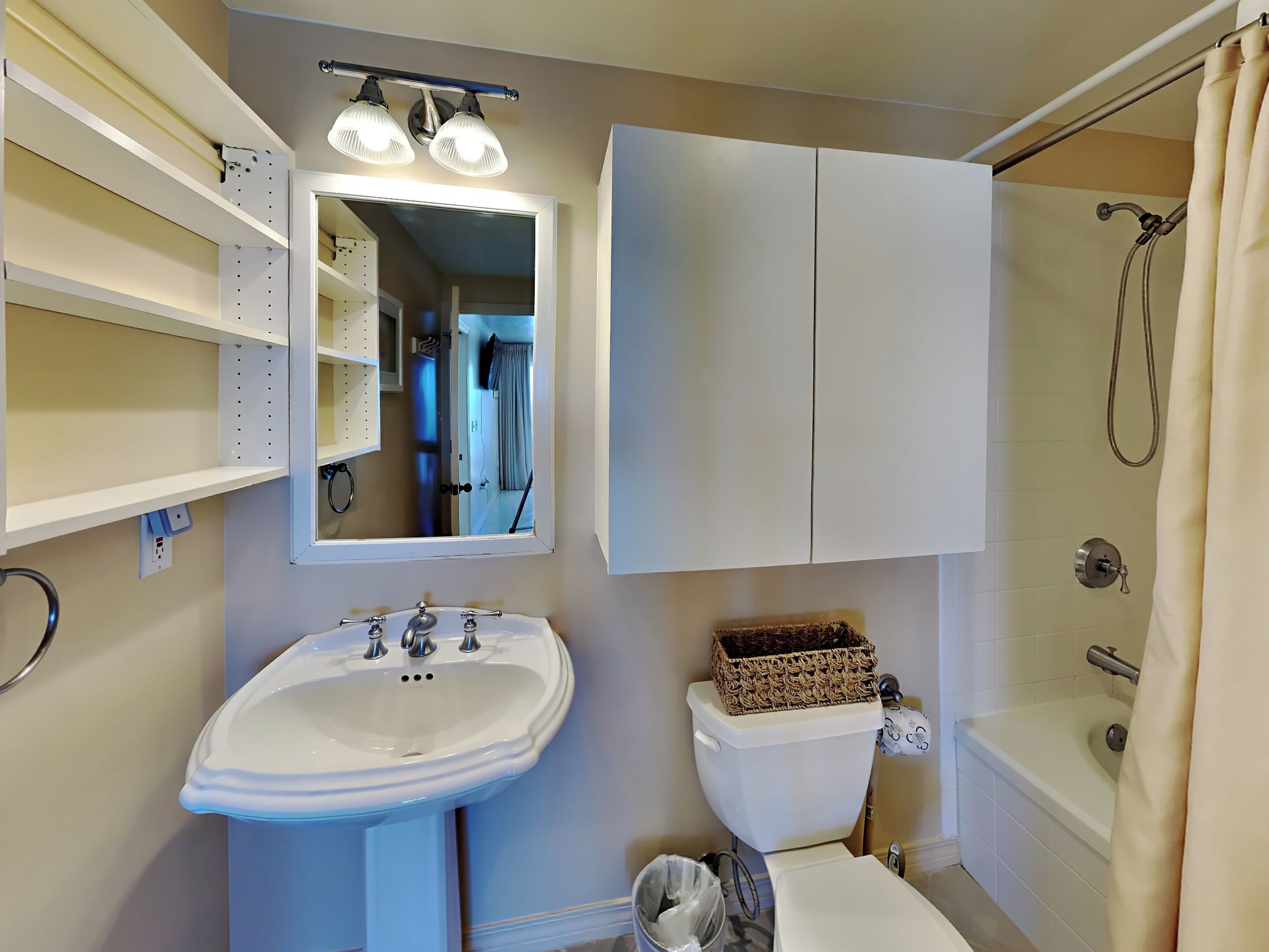 A bathroom with a white sink, a toilet, a shower, and a mirror.
