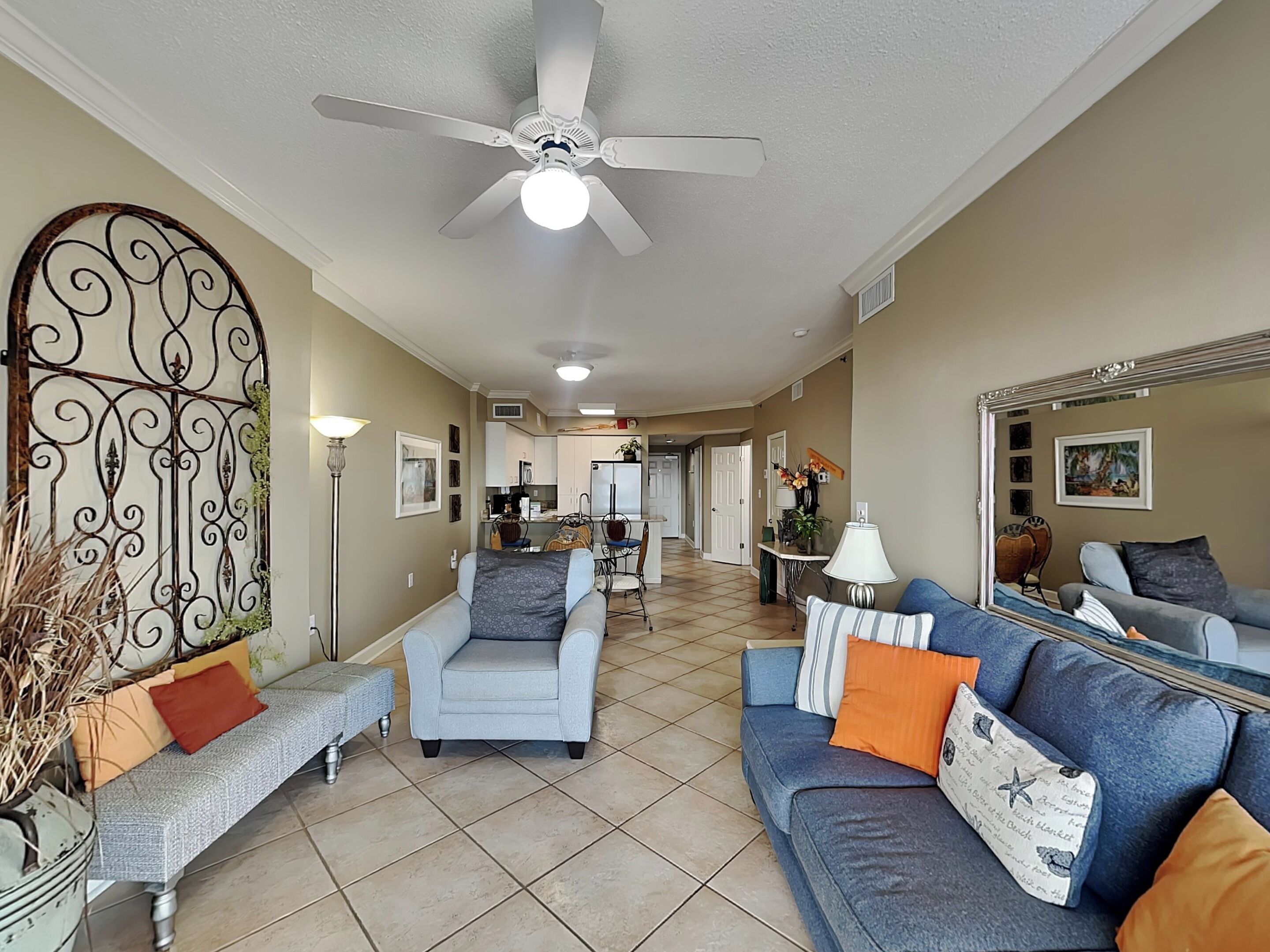A spacious living room with a ceiling fan, a sofa set, a coffee table, and a dining area in the background.