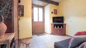 Ein Wohnzimmer mit Holztür, Fernseher auf einem Holzschrank und einer Zimmerpflanze.