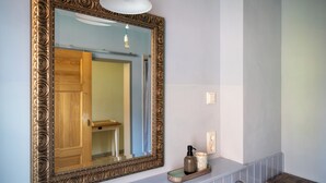 A bathroom with a large ornate mirror, a light fixture above it, and a small shelf with toiletries. - Stylish accommodation in a monument in the heart of Halberstadt's old town (Halberstadt)