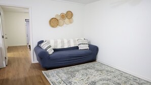 A room with a blue sofa, a patterned rug, and a wall with woven decorations.