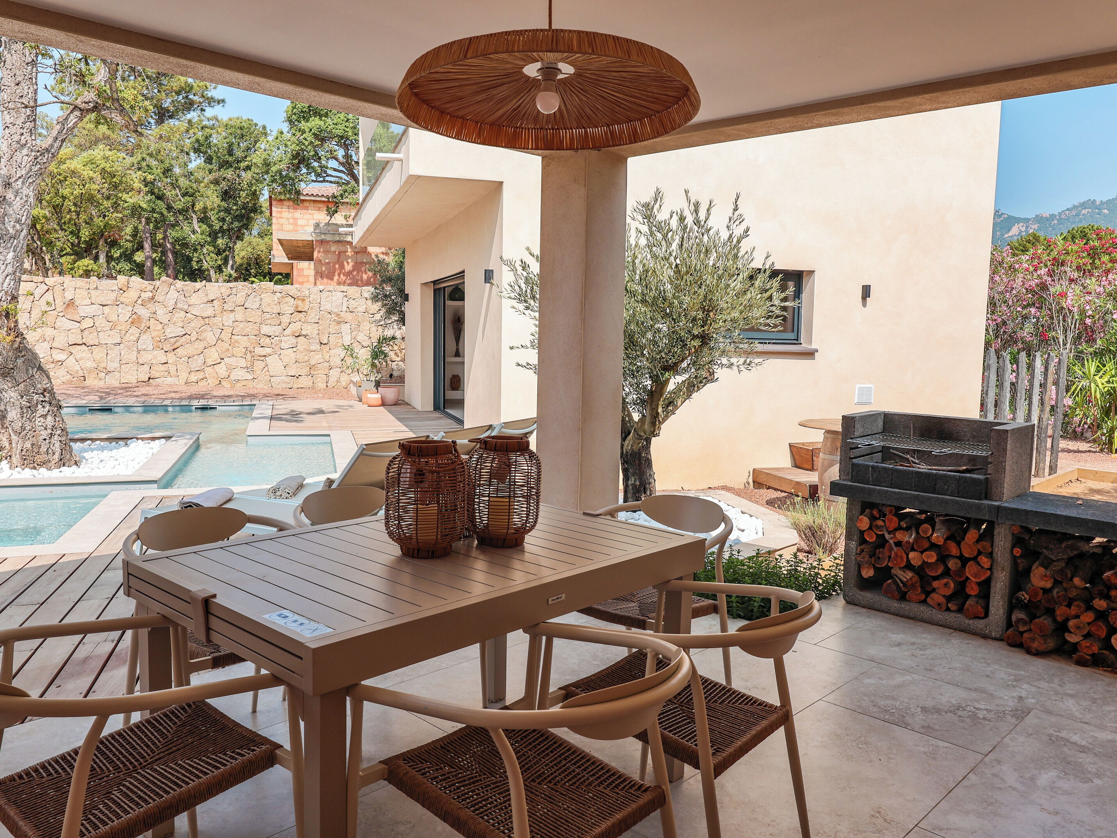 A patio with a table and chairs, a pool, and a barbecue area.