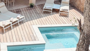 A wooden deck with a pool, lounge chairs, and a table with chairs.