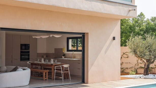 A modern house with an open-plan kitchen and dining area, a pool, and a patio.
