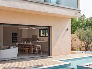 Una casa moderna con cucina e zona pranzo open space, piscina e patio.