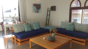 En stue med sofaarrangement, sofabord og spiseområde med bord og stole.