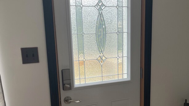 Une porte blanche avec un panneau de verre orné d’un motif géométrique.
