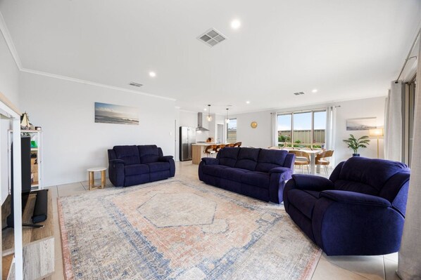 A spacious living area with a large rug, two sofas, and a dining area in the background.