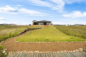 Een modern huis met een verharde oprit die leidt naar een houten terras.