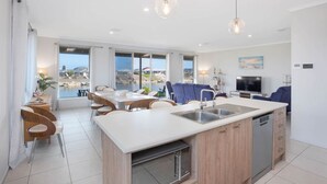 A modern kitchen with a central island, dining area with chairs, and a sofa.