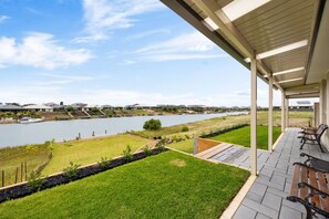 Een overdekt terras met uitzicht op een meer en huizen in de verte.