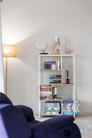 A bookshelf with various books and decorative items, a lamp, and a sailboat model on top.