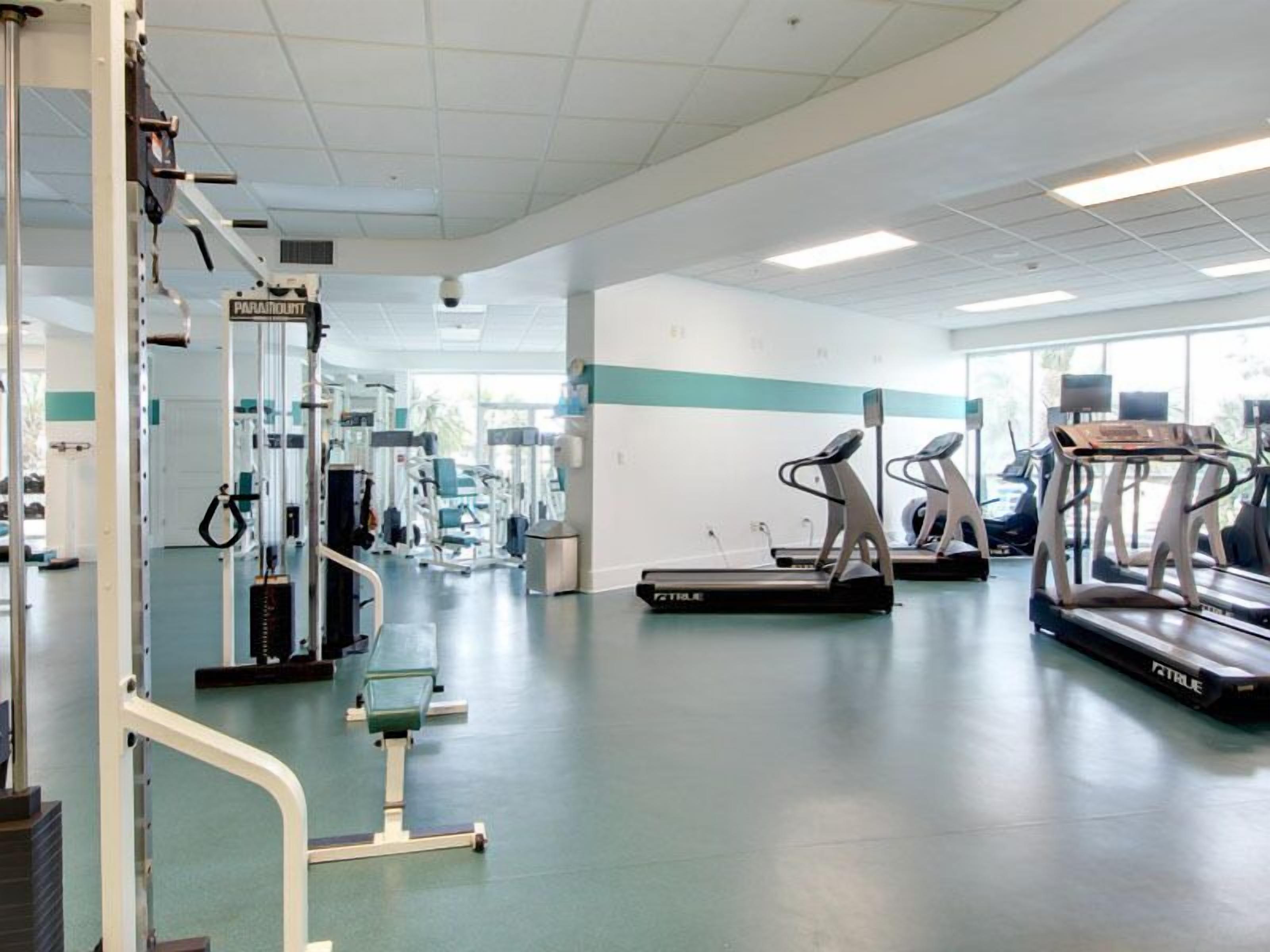 A gym with cardio machines, weightlifting equipment, and a mirrored wall.