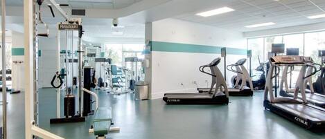 A gym with cardio machines, weightlifting equipment, and a mirrored wall.