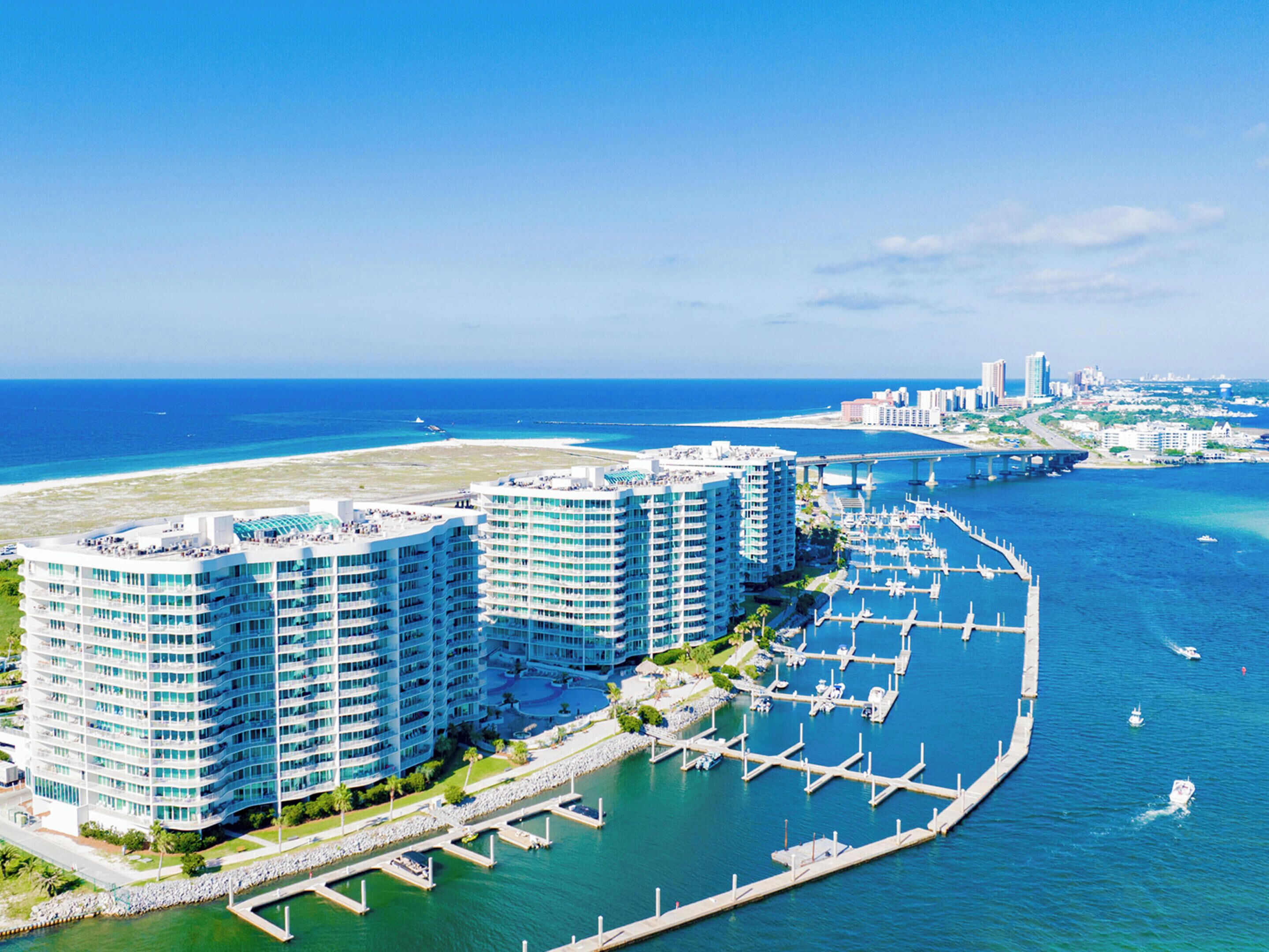 A high-rise hotel with multiple balconies overlooking a marina and the ocean.