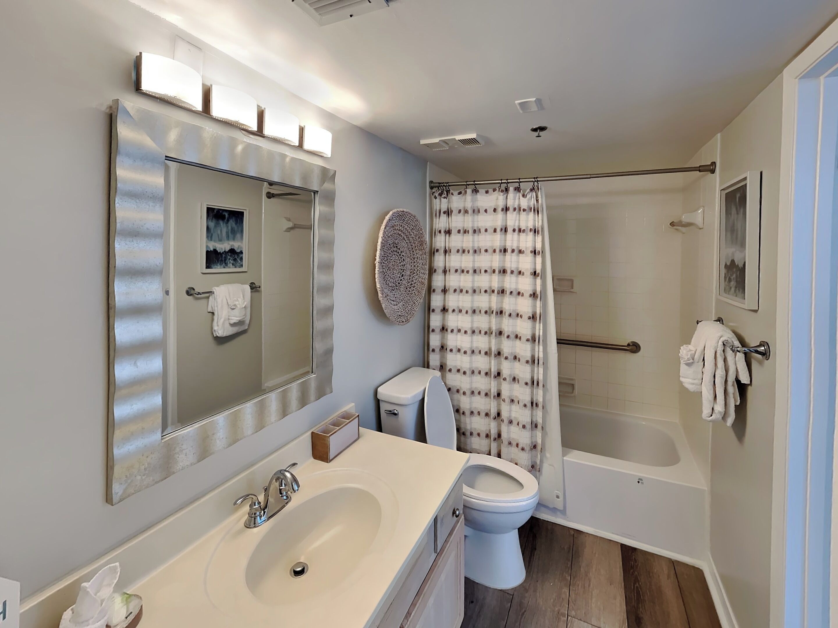 A bathroom with a large mirror, a sink, a toilet, and a shower area.