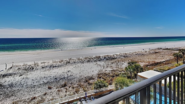 A beach view from a balcony with a pool and a sandy area with sparse vegetation. - Sea Oats #603 by Southern Vacation Rentals (Fort Walton Beach)