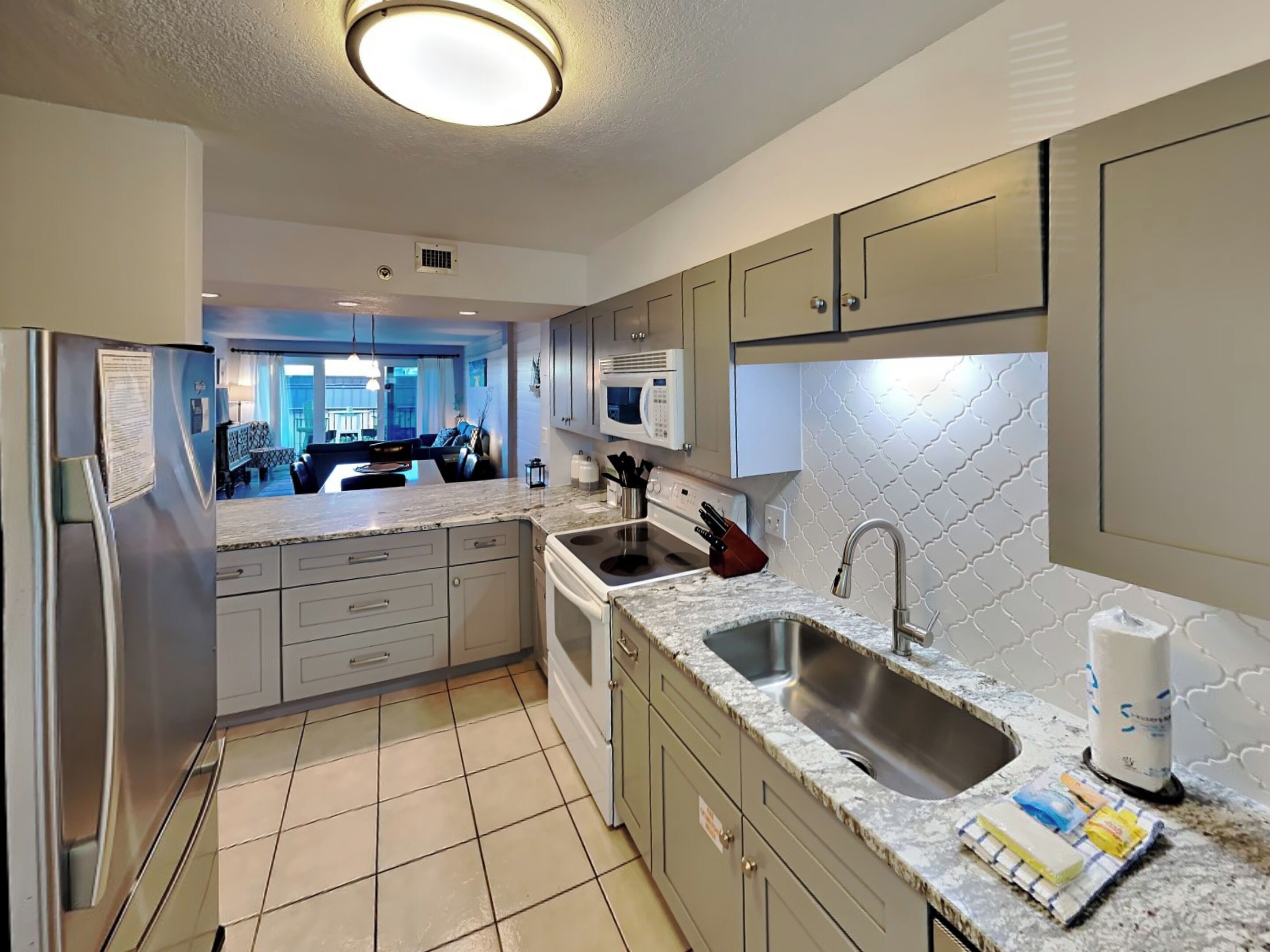 A modern kitchen with a central island, stainless steel appliances, and a tiled backsplash.