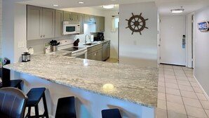 Una cocina moderna con encimeras de granito, electrodomésticos de acero inoxidable y una zona de bar con taburetes.