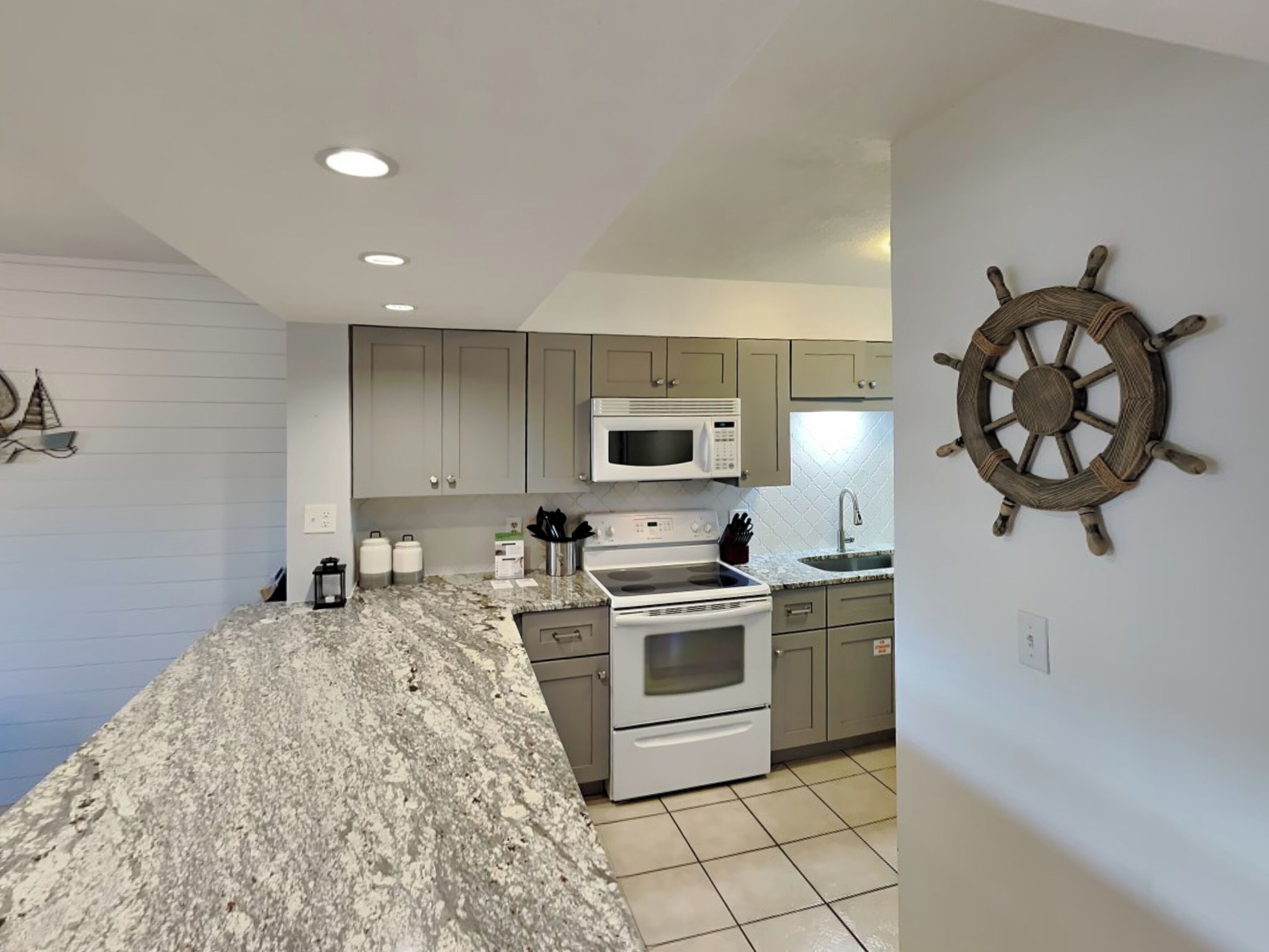 A kitchen with granite countertops, stainless steel appliances, and light gray cabinets.