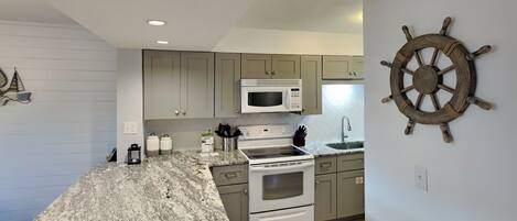 A kitchen with granite countertops, stainless steel appliances, and light gray cabinets.