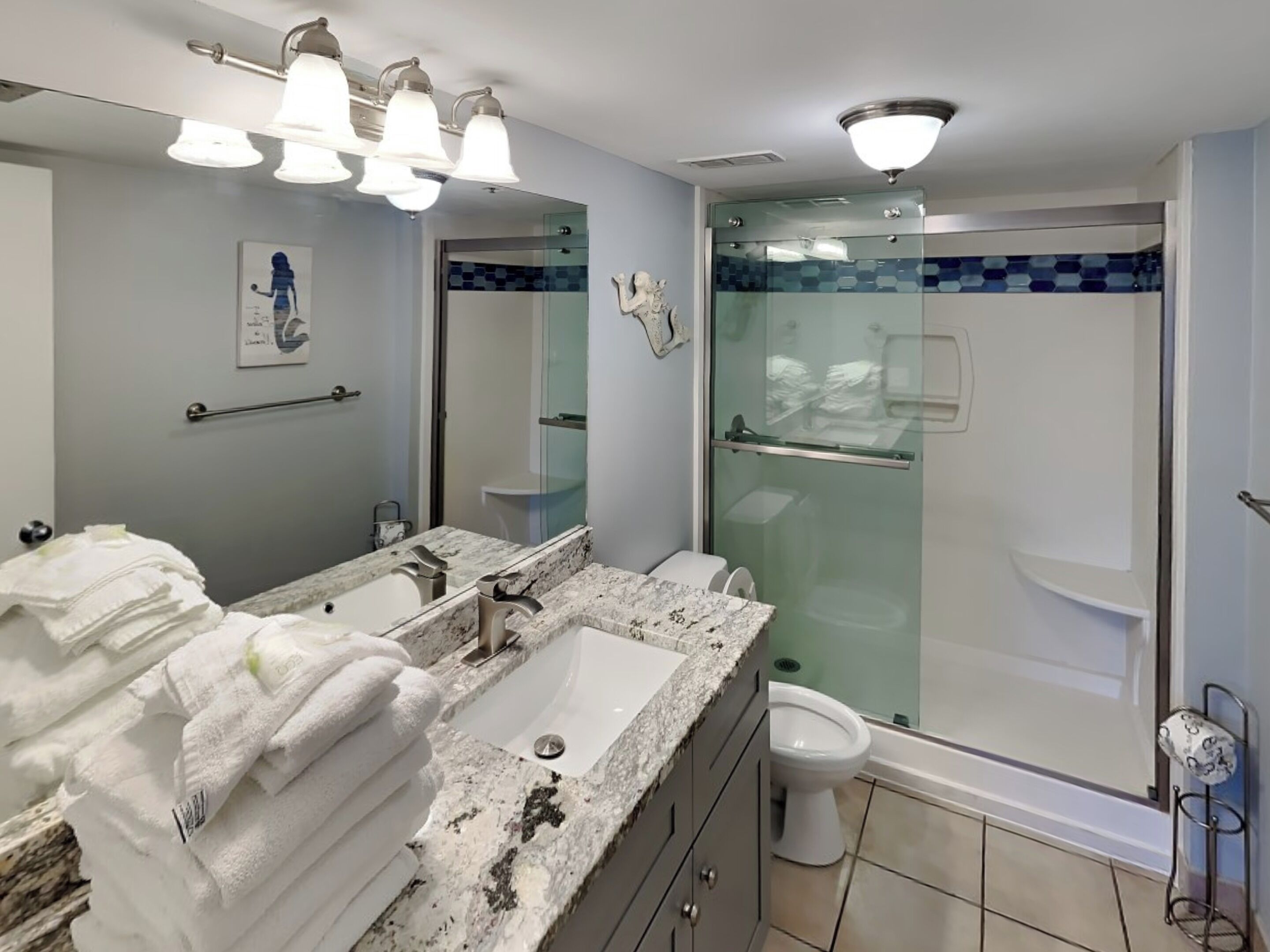 A modern bathroom with a dual sink vanity, a large mirror, and a glass-enclosed shower.