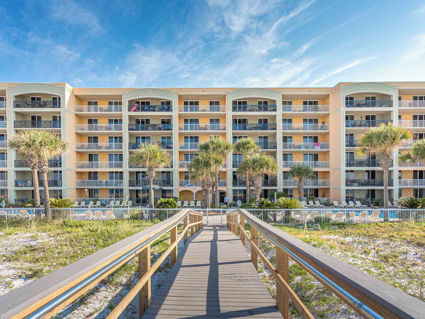 Un hôtel à plusieurs étages doté de balcons, d’une promenade en bois et d’un espace piscine.