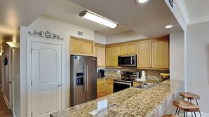 Una cocina moderna con encimeras de granito, electrodomésticos de acero inoxidable, armarios de madera y un microondas integrado.