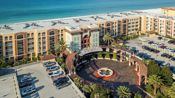 Un hotel con patio central, varios niveles de estacionamiento y vista a la playa.