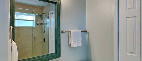 A bathroom with a large mirror, a sink, a toilet, and a shower area.
