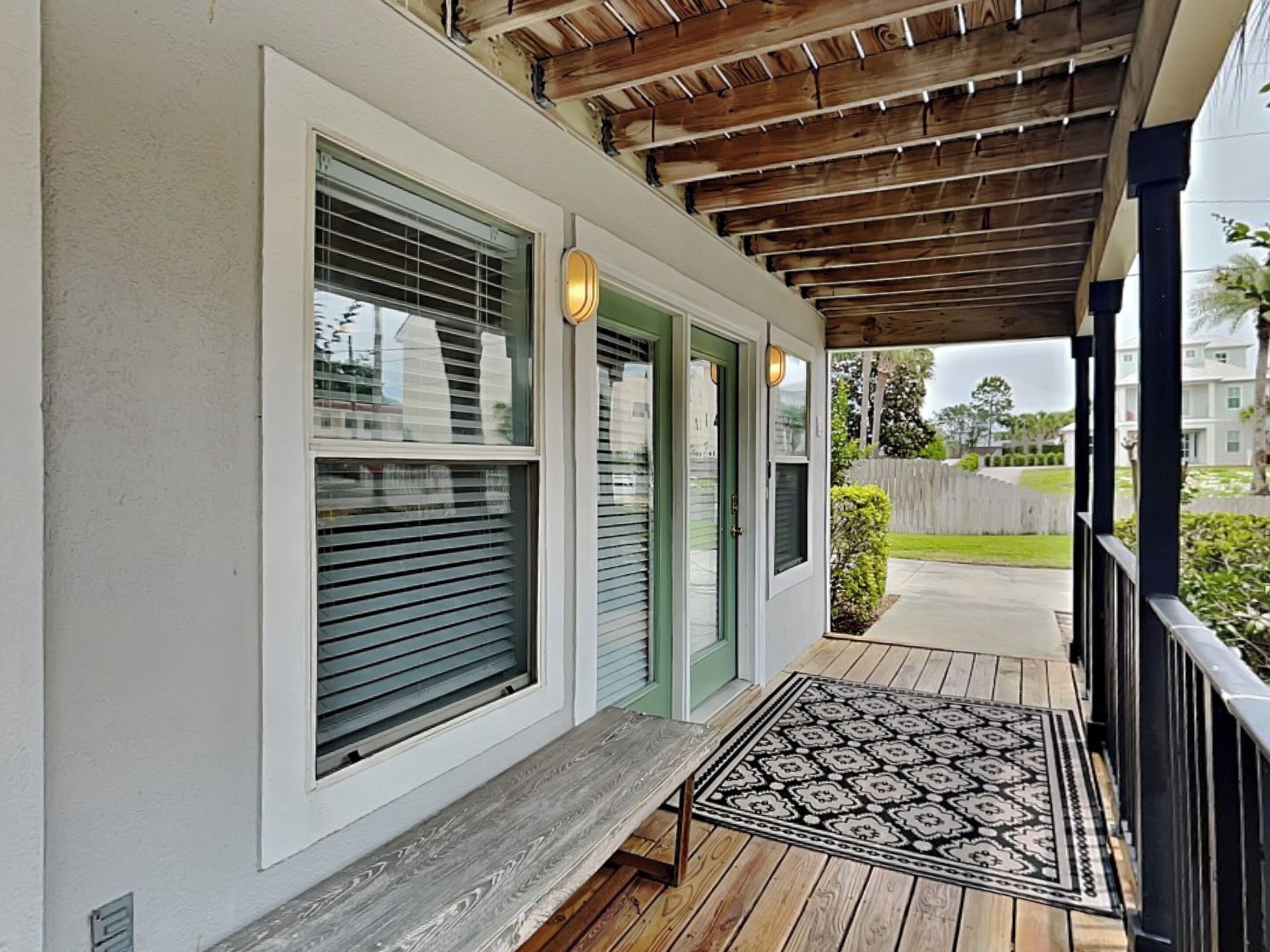 A covered porch with a wooden deck and a patterned rug.