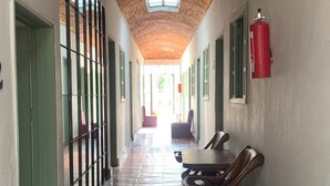Un couloir avec un plafond en briques, un sol carrelé et un extincteur fixé au mur.