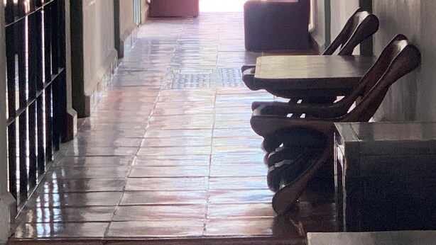 Un couloir avec un sol carrelé, un plafond en briques et un extincteur fixé au mur.