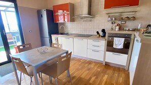 Une cuisine moderne avec des meubles blancs, une table à manger en bois et un four encastré.
