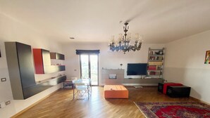 Un salon moderne avec un coin repas, une grande télévision et un balcon.