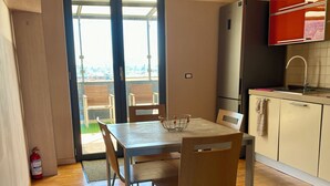 Une cuisine moderne avec un coin repas, un plancher en bois et une vue à travers la porte vitrée.