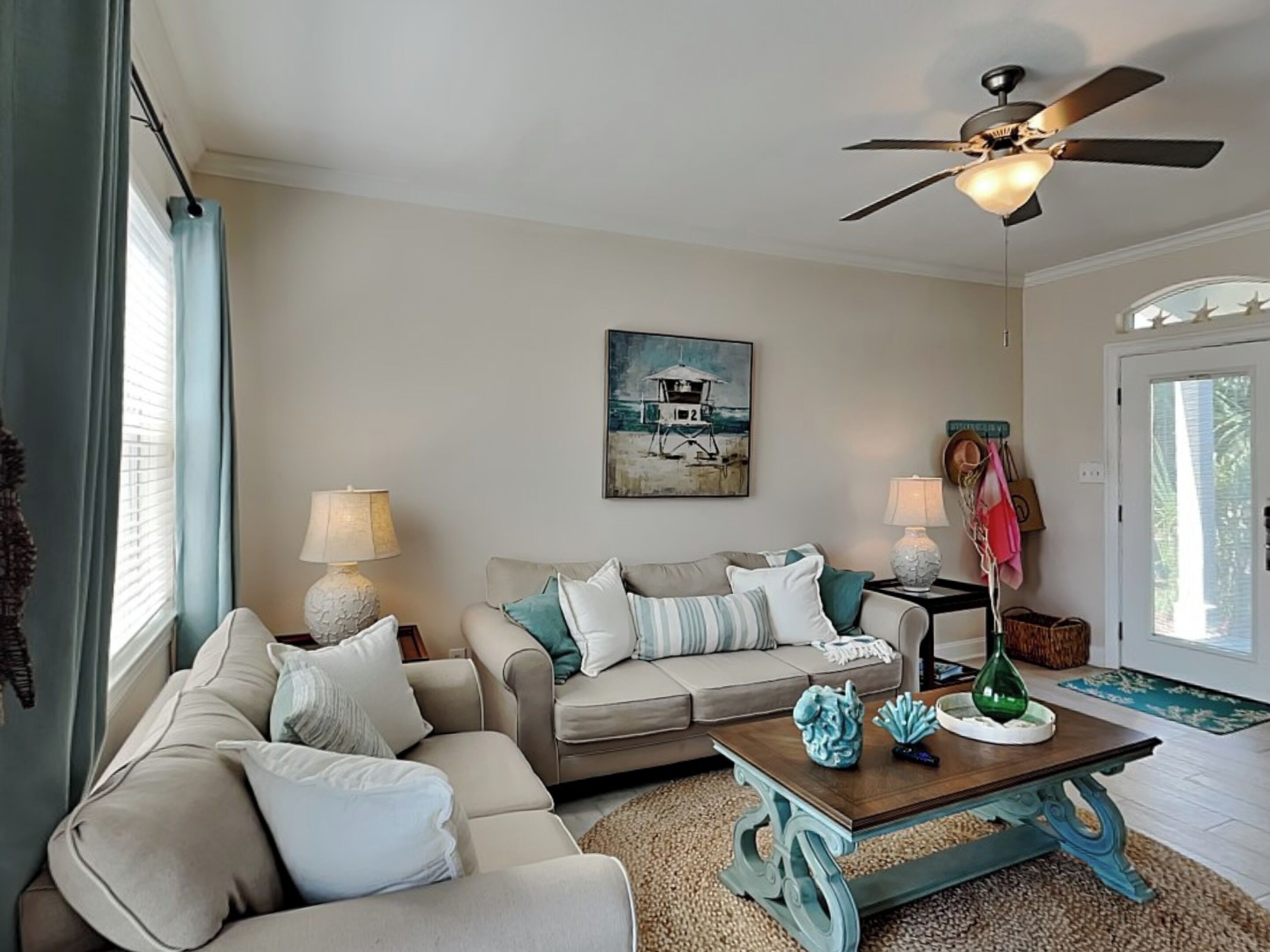 A living room with a beige sofa, a coffee table, and a ceiling fan.