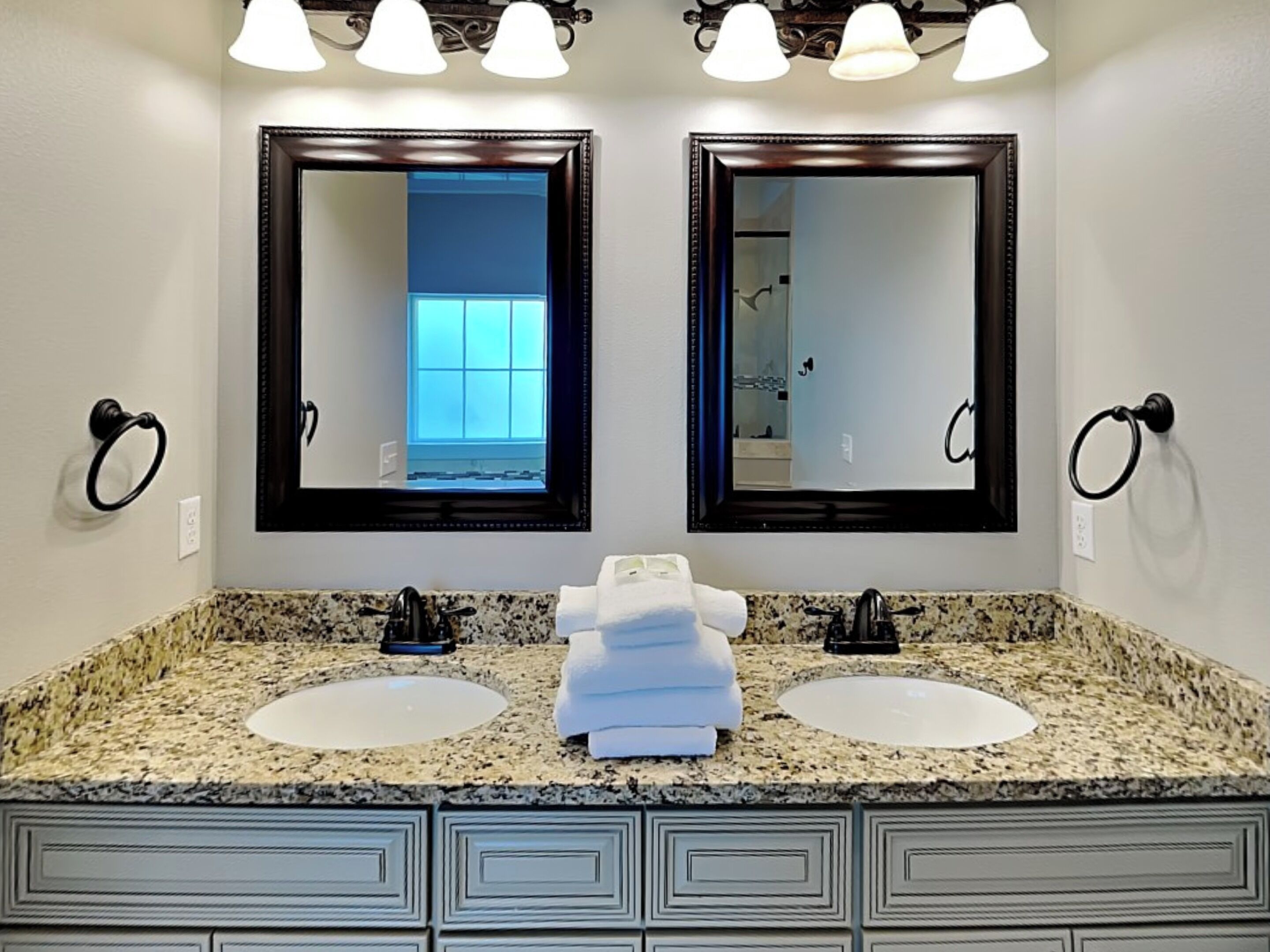 A bathroom with two sinks, a large mirror, and a window.