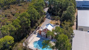 An aerial view of a residential area with a swimming pool, surrounded by trees and houses. - Frangista Sanctuary by Southern Vacation Rentals (Miramar Beach)