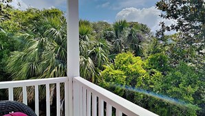 A balcony with a white railing, lush greenery, and a clear sky. - Palms North #7B by Southern Vacation Rentals (Santa Rosa Beach)