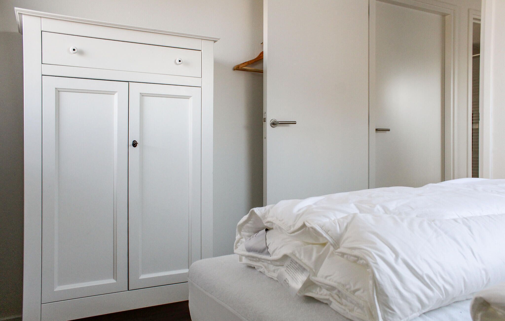 Un dormitorio con cama, armario y puerta.