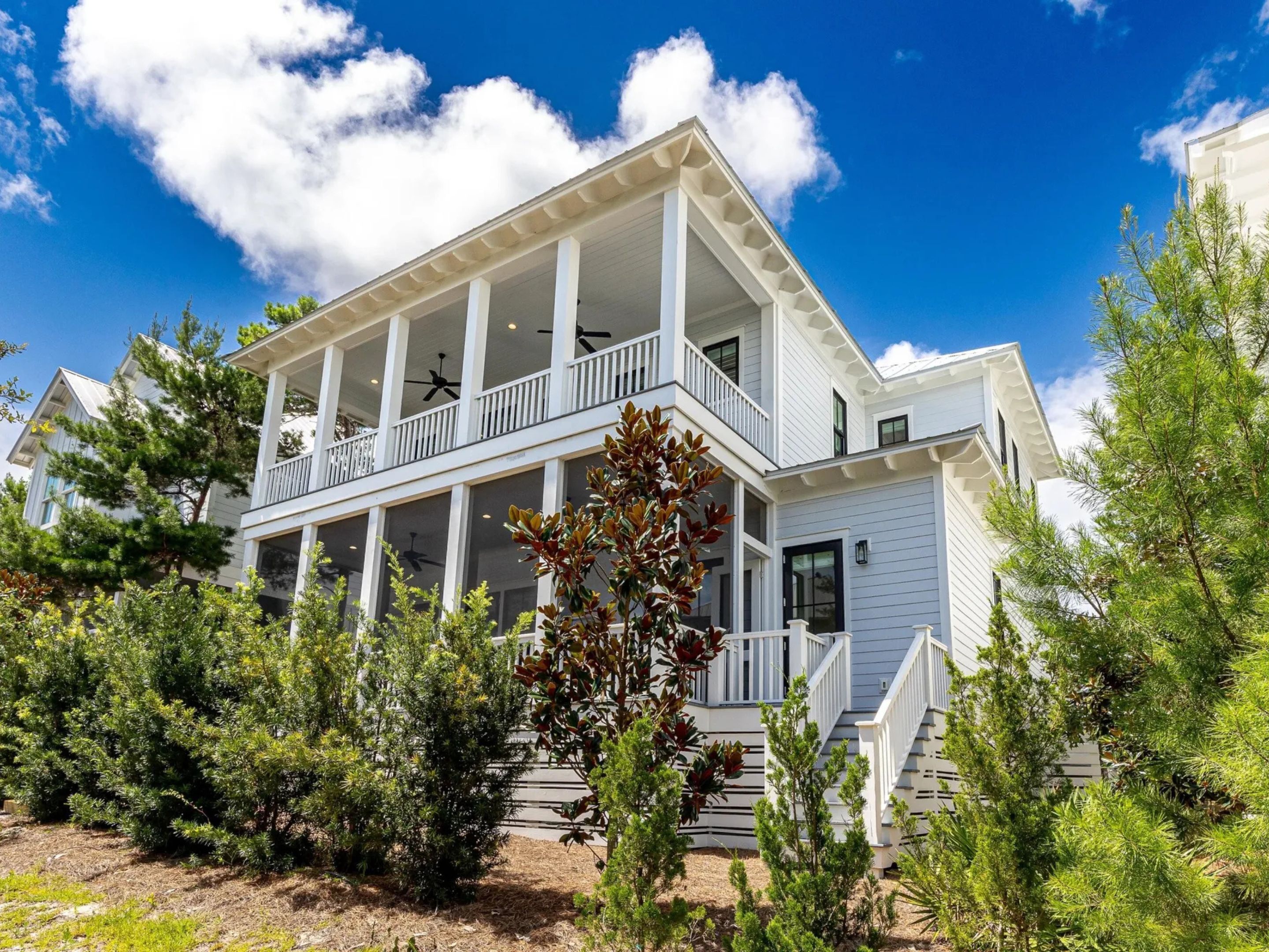 A two-story house with a balcony, surrounded by trees.