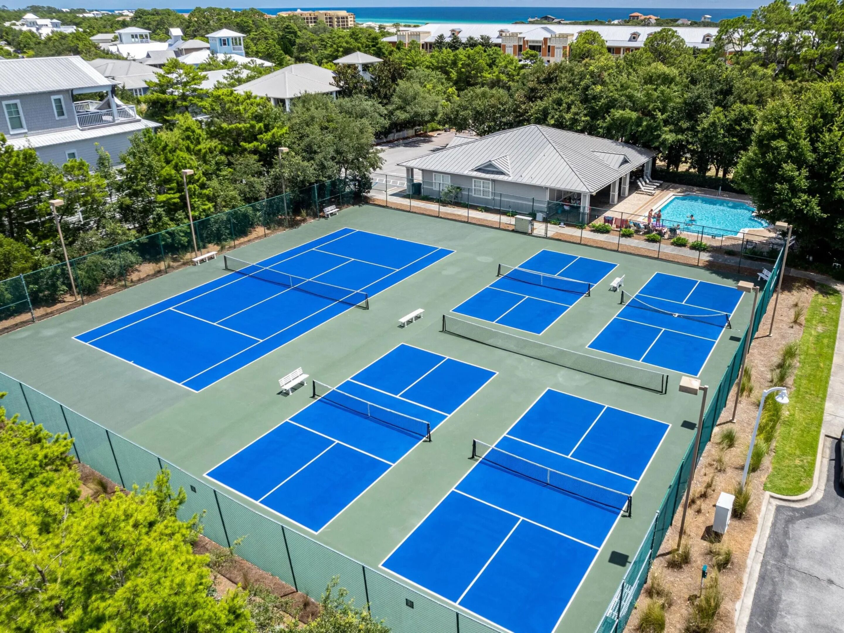 Una pista de tennis a l'aire lliure envoltada d'arbres i edificis.
