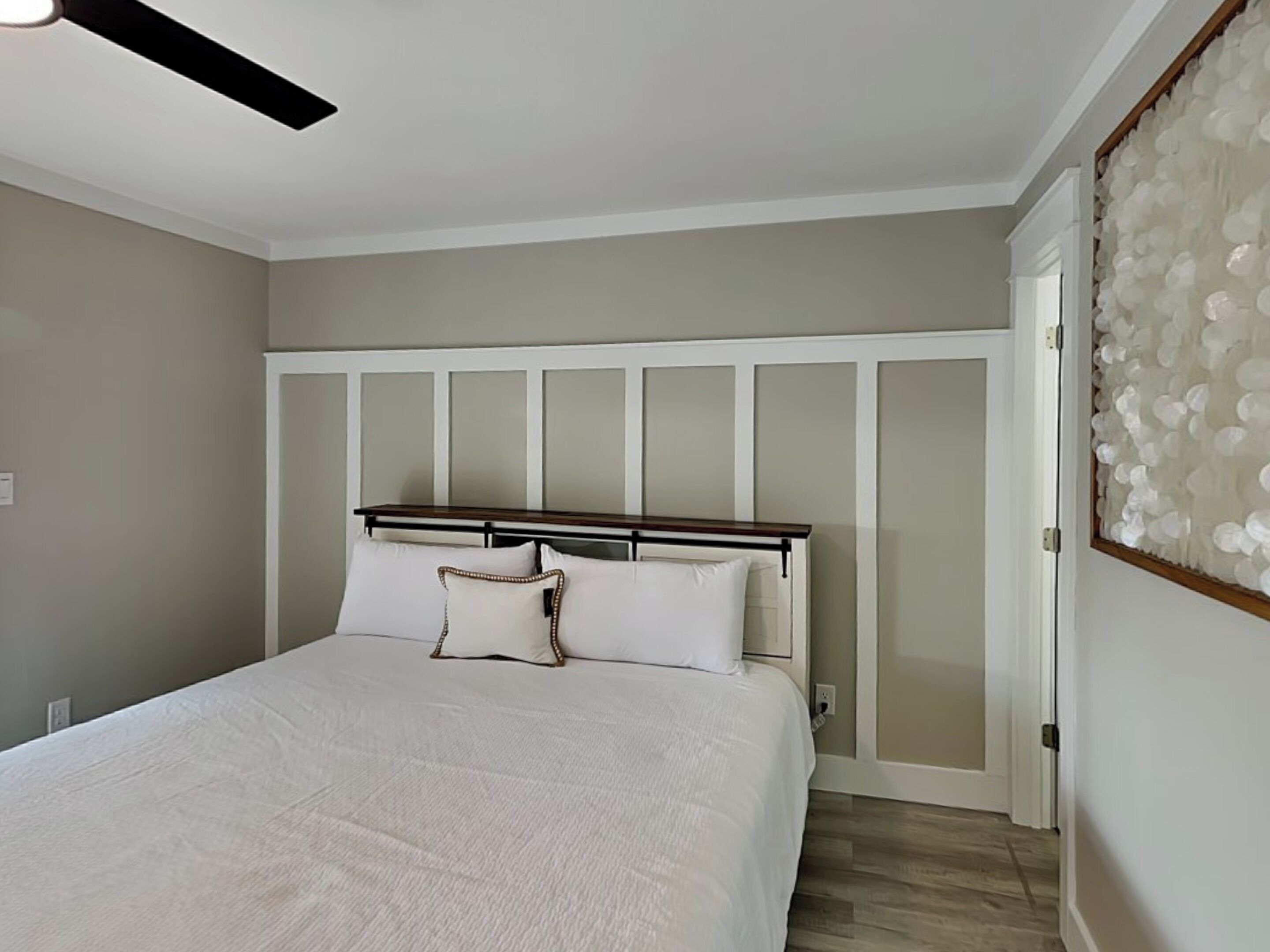 A bedroom with a bed, a headboard, a ceiling fan, and a door with frosted glass panels.